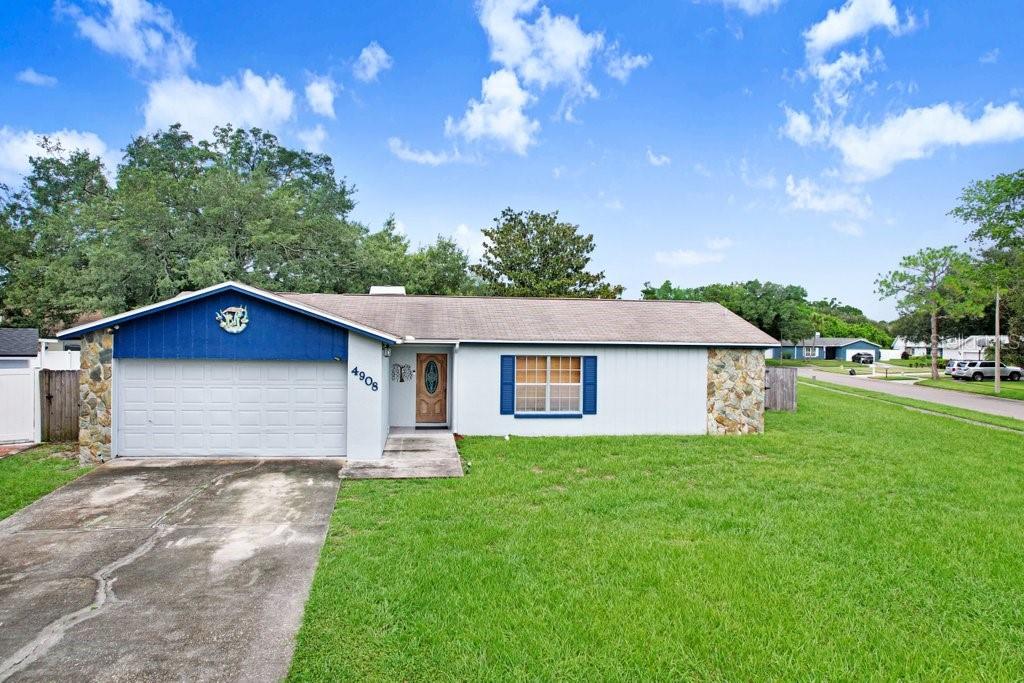 A single-story house with a white facade, blue accents, and stone-faced corners — 4908 CROCKETT COURT, TAMPA, FL