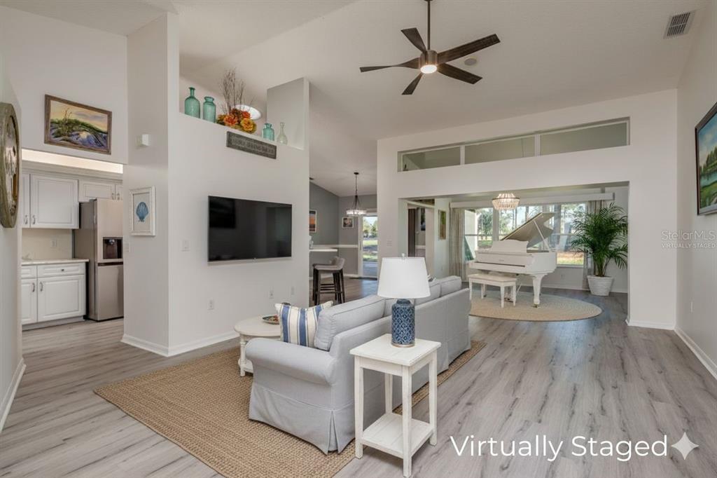 A living room with light wood floors, a white sofa, and a grand piano — 9742 OAKWOOD HILLS COURT, NEW PORT RICHEY, FL