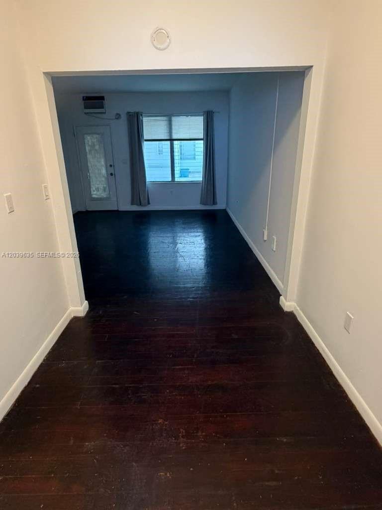 A view through a doorway into a room with dark wood flooring and a window — MIAMI BEACH, FL