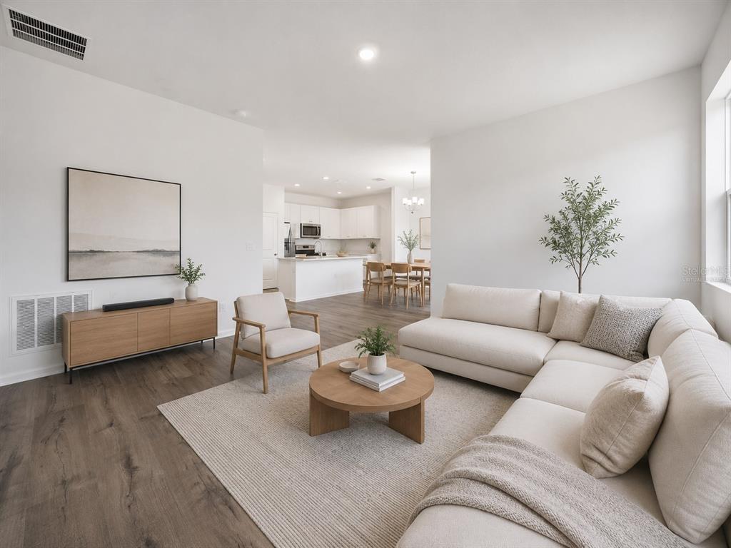 A bright living room with a sectional sofa, round coffee table, and open-concept kitchen — 5719 HIAWASSEE ROAD, OKAHUMPKA, FL