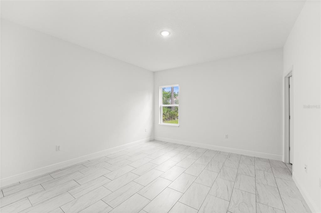 An empty bedroom features white walls, light-colored tile flooring, and a single window — 9324 N FAIRY LILLY DR, CITRUS SPRINGS, FL