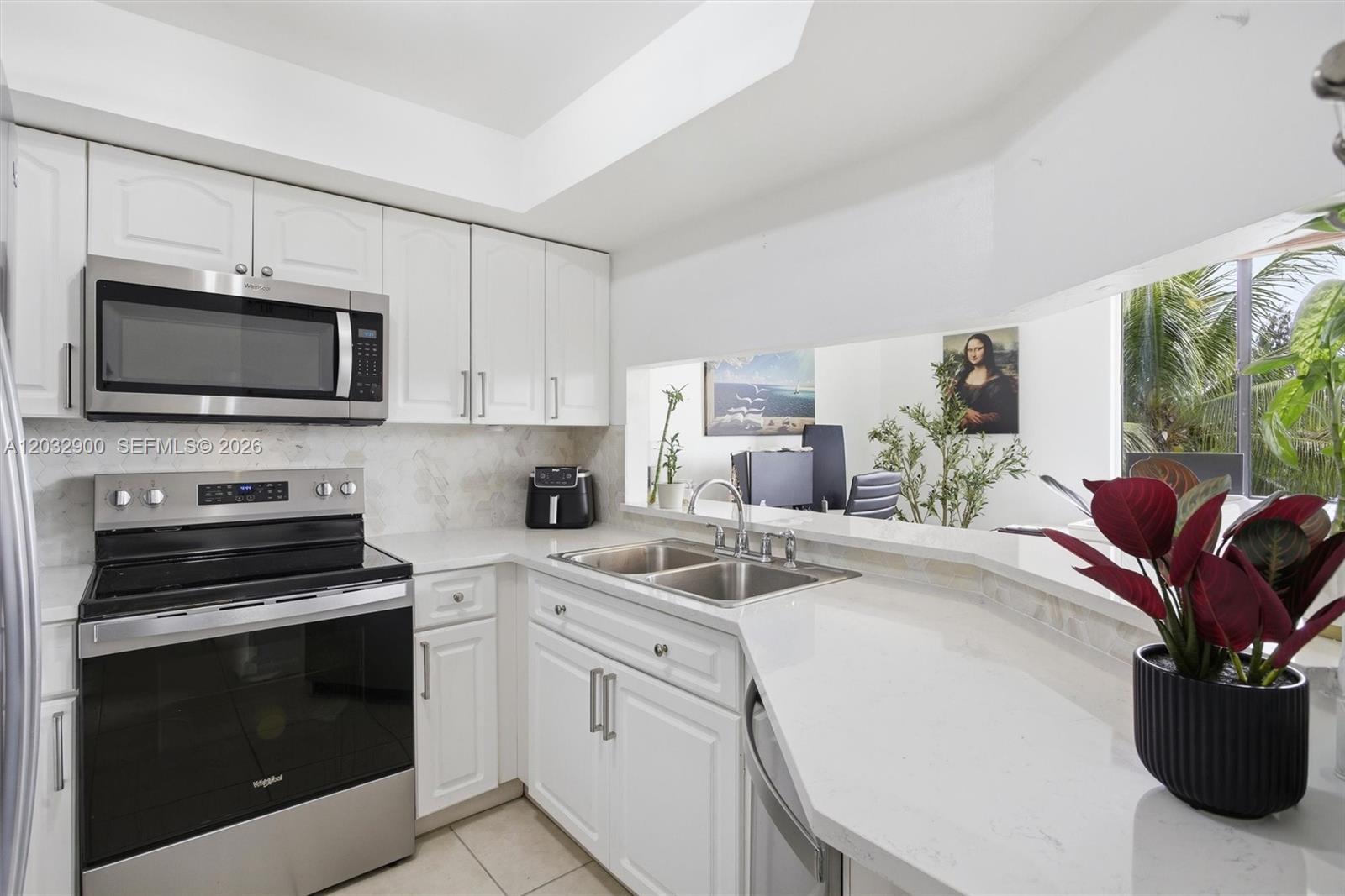 A white kitchen features stainless steel appliances, quartz countertops, and a pass-through window — 8335 SW 152nd Ave # 411, Miami FL 33193, MIAMI, FL