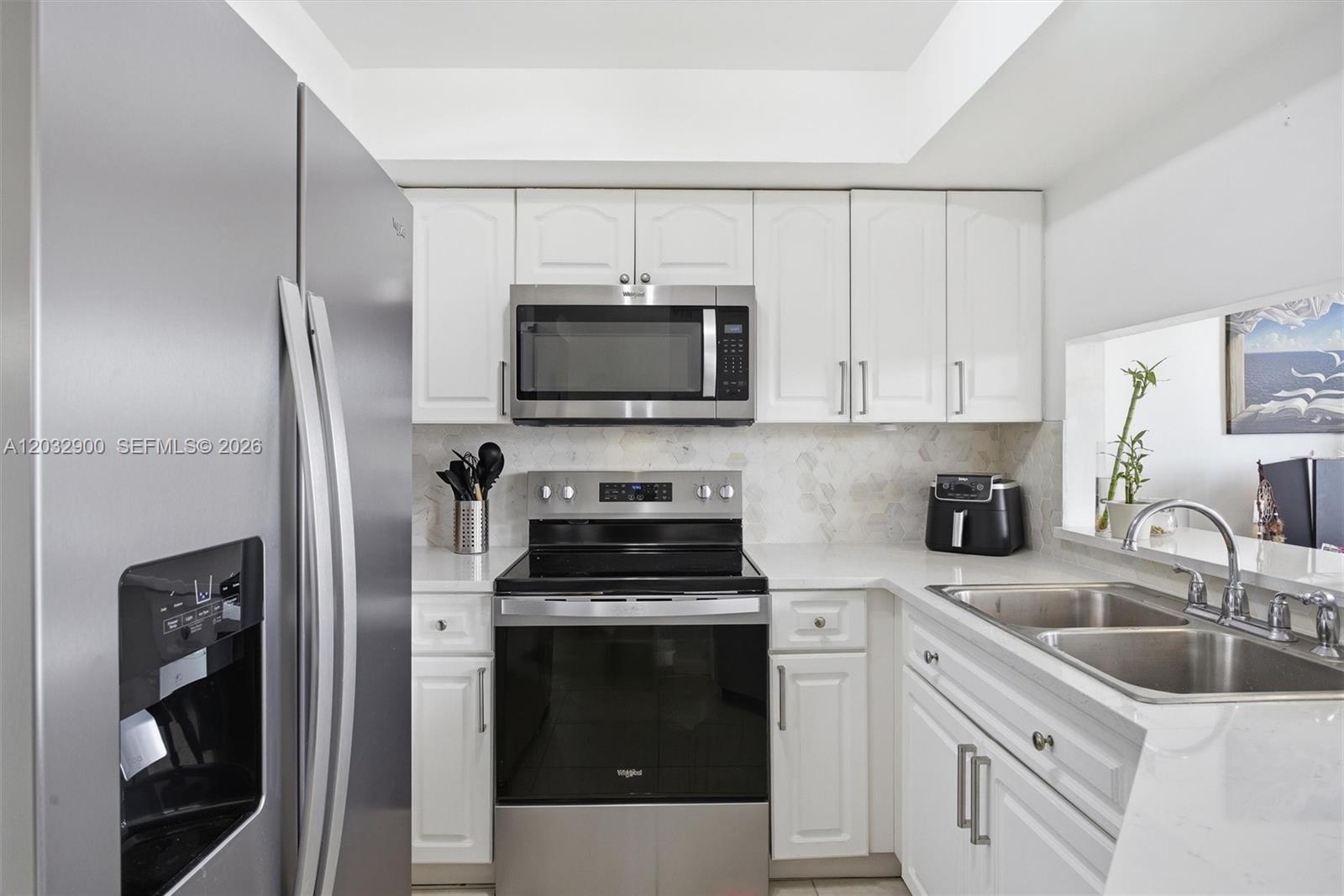 A kitchen features white cabinets, stainless steel appliances, and a light-colored hexagonal tile backsplash — 8335 SW 152nd Ave # 411, Miami FL 33193, MIAMI, FL