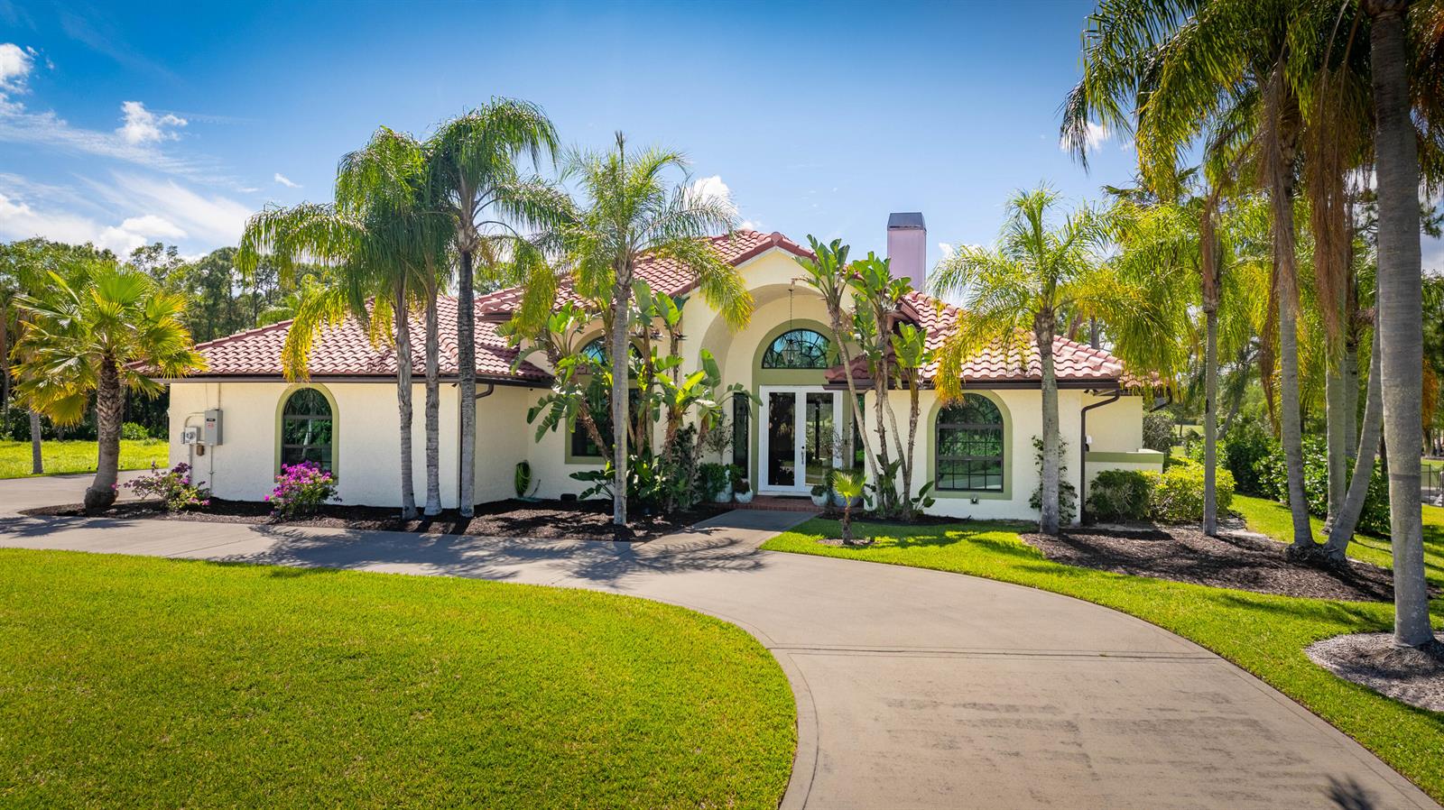 A single-story house with a red tile roof, arched windows, and a curved concrete driveway — 18680 SE Old Trail Drive E, Jupiter FL 33478, JUPITER, FL