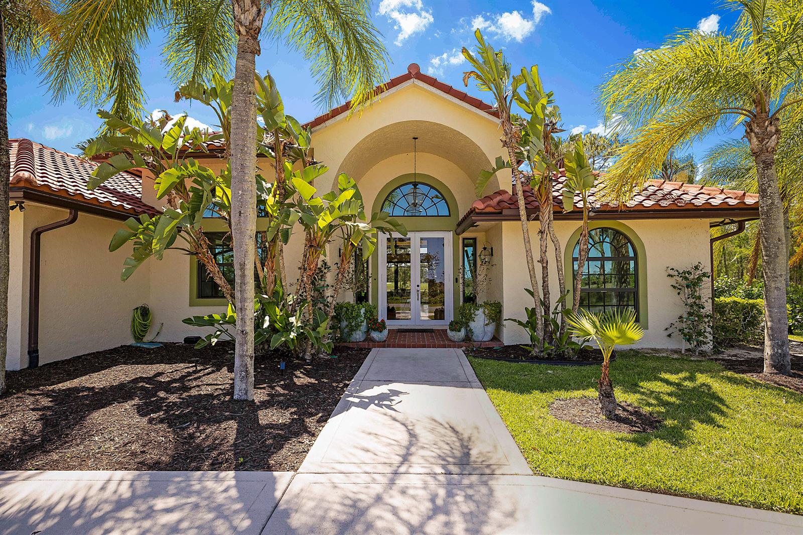 A single-story house with a stucco exterior, arched entryway, and a tiled roof — 18680 SE Old Trail Drive E, Jupiter FL 33478, JUPITER, FL