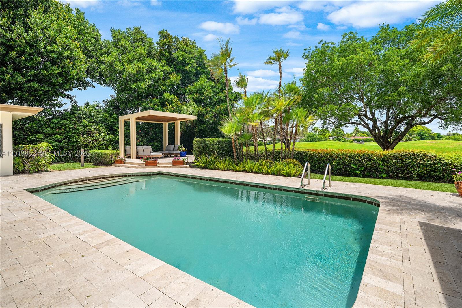 A swimming pool with a stone deck sits in front of a shaded patio area — 4301 Sanders St, Hollywood FL 33021, HOLLYWOOD, FL