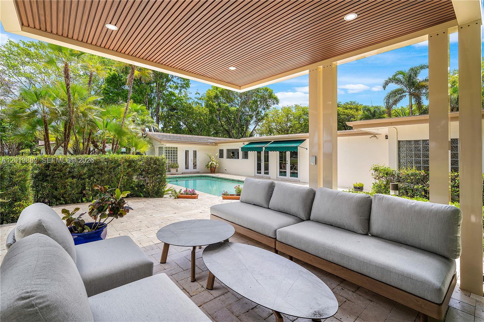 A covered patio features gray outdoor seating and two coffee tables overlooking a swimming pool — 4301 Sanders St, Hollywood FL 33021, HOLLYWOOD, FL