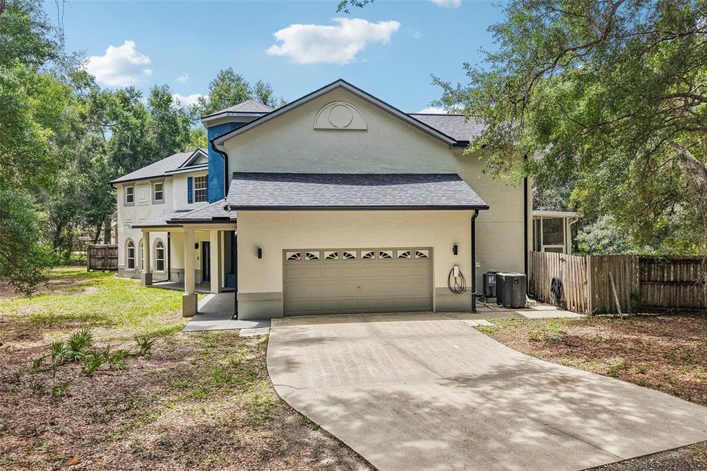 A two-story house with a beige stucco exterior, a gray garage door, and a driveway — 4920 SW 78TH AVENUE, BUSHNELL, FL