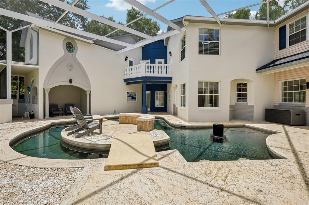 An enclosed patio features a uniquely shaped pool with a central island and a fountain — 4920 SW 78TH AVENUE, BUSHNELL, FL
