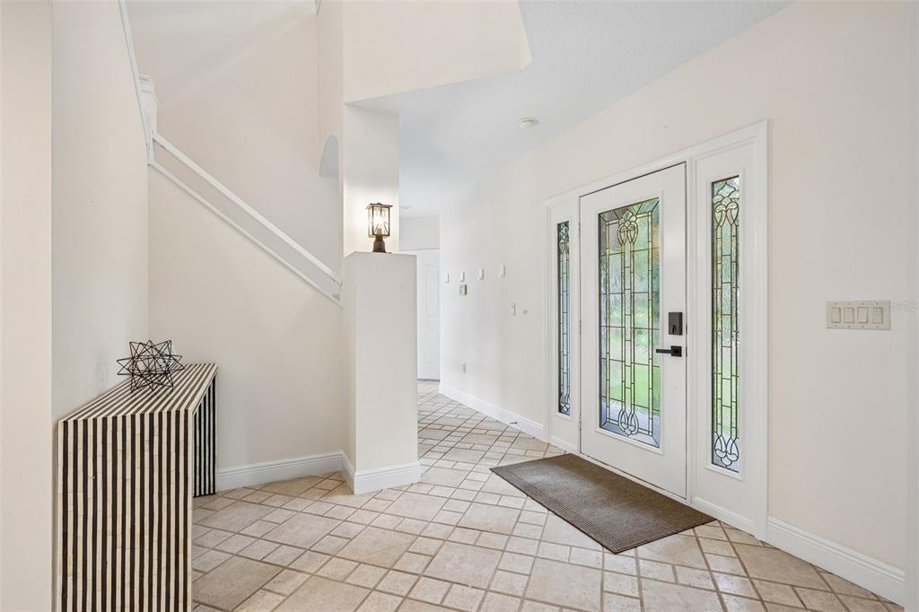 An entryway features a tiled floor, a white front door with glass panels, and stairs — 4920 SW 78TH AVENUE, BUSHNELL, FL