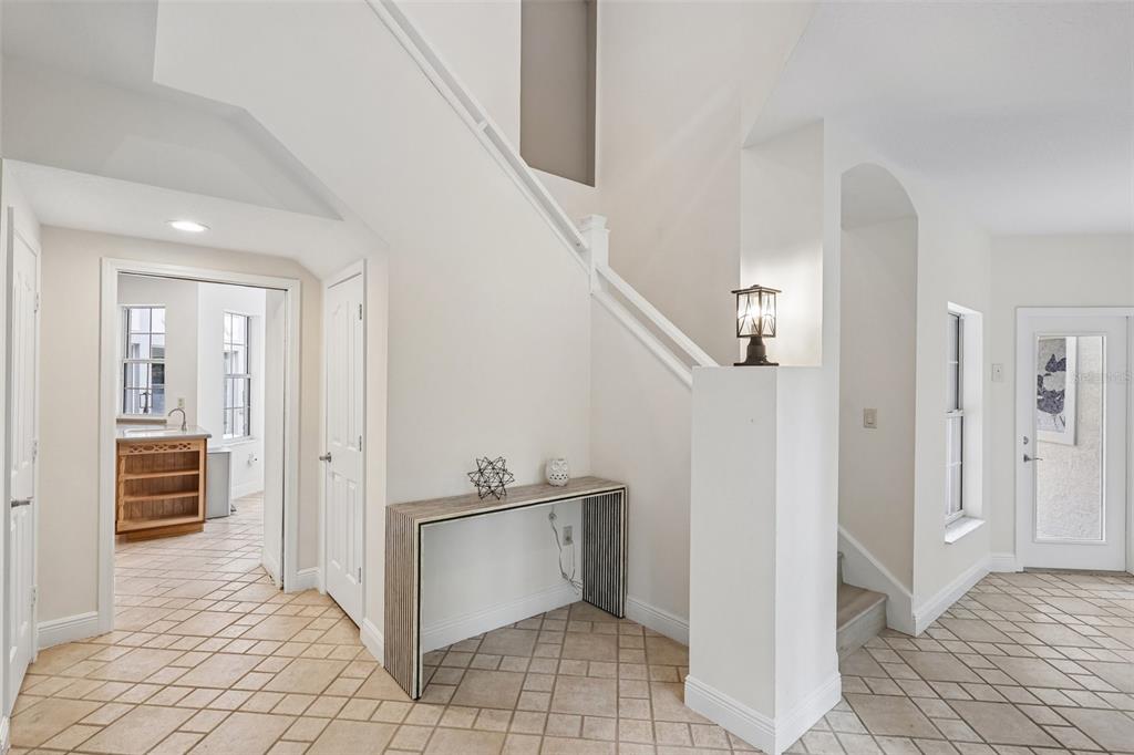 An entryway features a staircase, a modern console table, and tile flooring — 4920 SW 78TH AVENUE, BUSHNELL, FL
