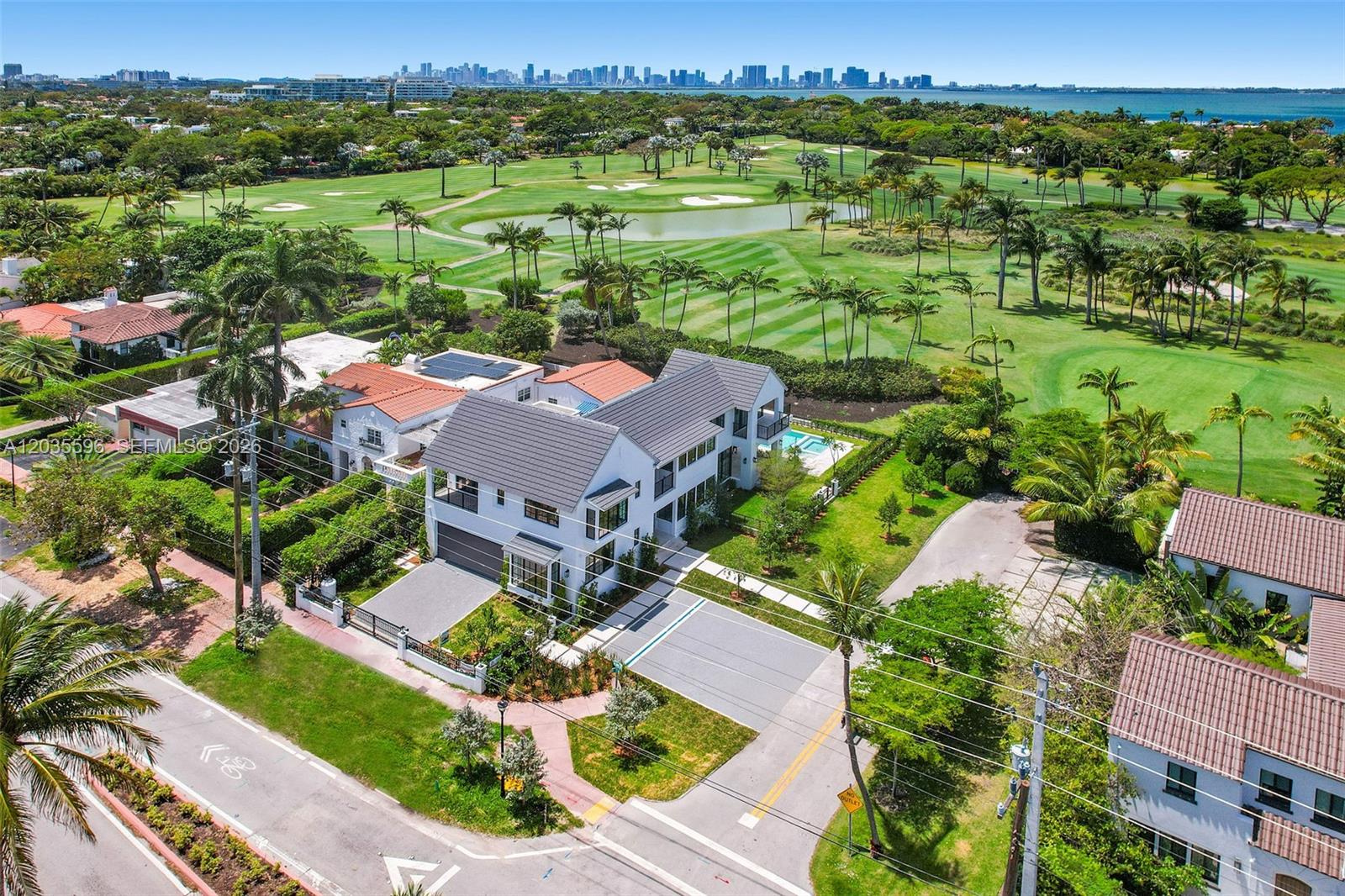 An aerial view shows a modern white house with a dark roof near a golf course — 5262 La Gorce Dr, Miami Beach FL 33140, MIAMI BEACH, FL