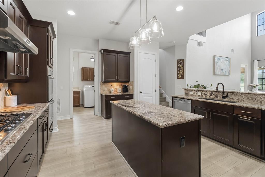 A kitchen with dark wood cabinets, granite countertops, a center island, and stainless steel appliances — 9918 HATTON CIRCLE, ORLANDO, FL