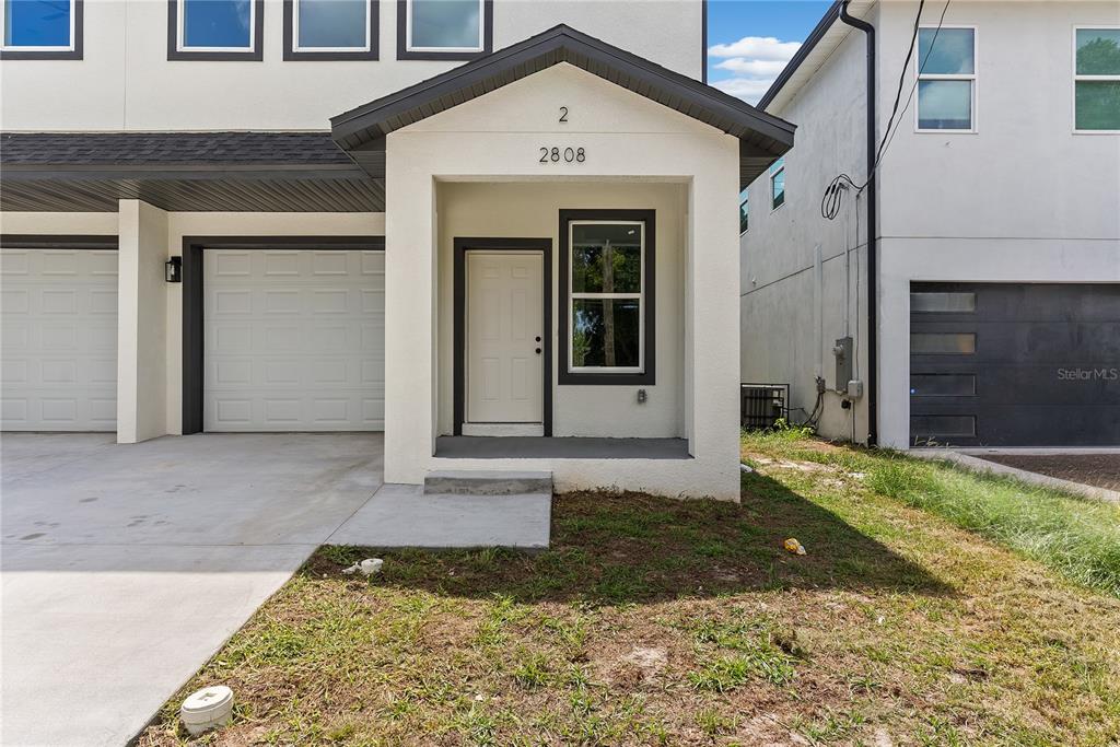 The exterior shows a white townhome with a covered entryway, a window, and a garage — 2808 N 29TH STREET UNIT 2, TAMPA, FL