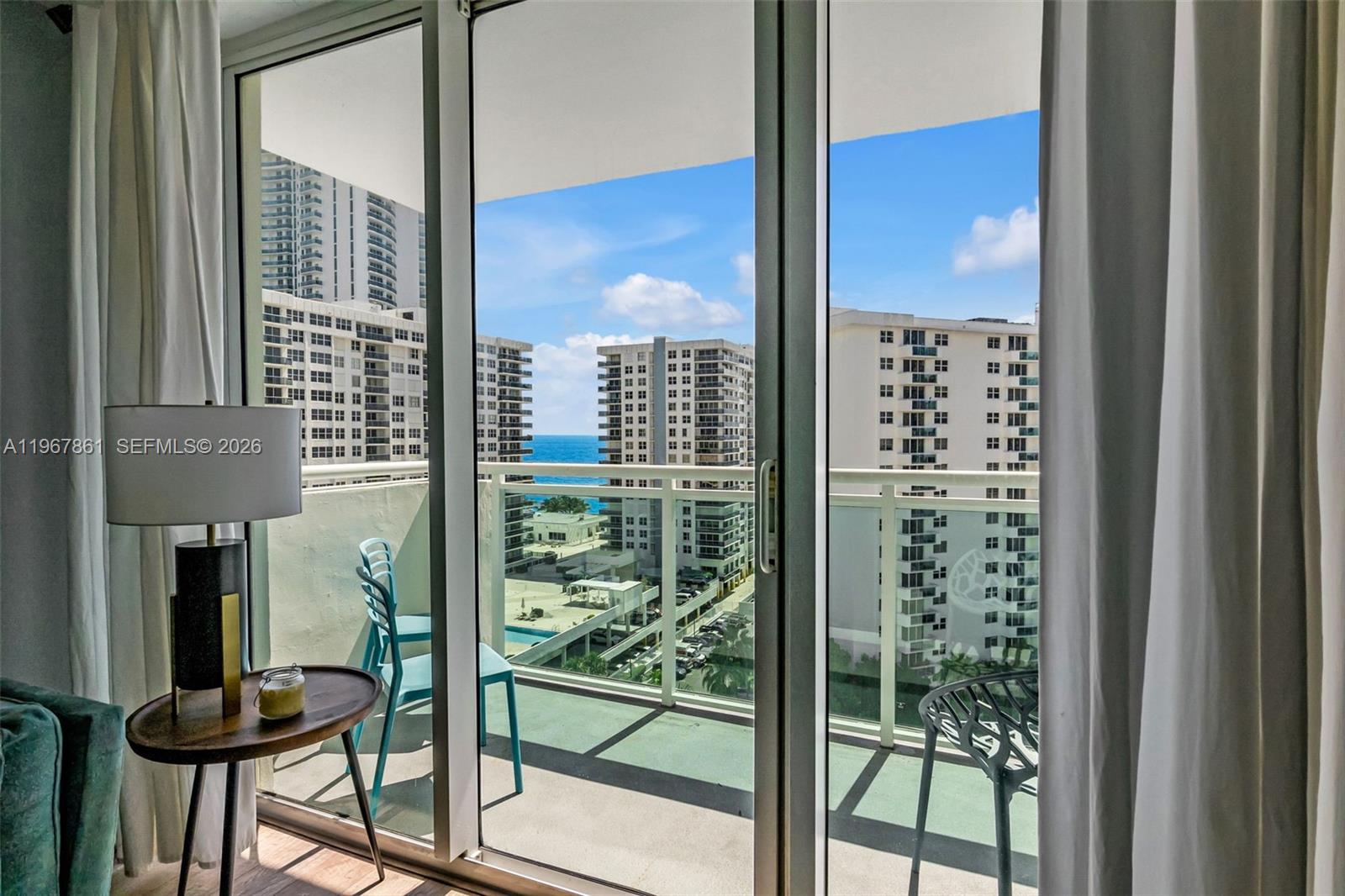 A view of a balcony with outdoor seating overlooking high-rise buildings and the ocean — 3000 S Ocean Dr # 1122, Hollywood FL 33019, HOLLYWOOD, FL