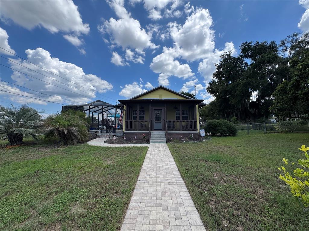 A yellow house with a front porch and a paved walkway sits on a lawn — 398 VIRGINIA STREET, FROSTPROOF, FL