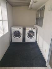 A laundry room with two white front-load appliances sitting on a raised platform — 189 Seville # 189, Delray Beach FL 33446, DELRAY BEACH, FL