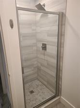 A walk-in shower features a glass door, light-colored tile walls, and a square shower head — 189 Seville # 189, Delray Beach FL 33446, DELRAY BEACH, FL