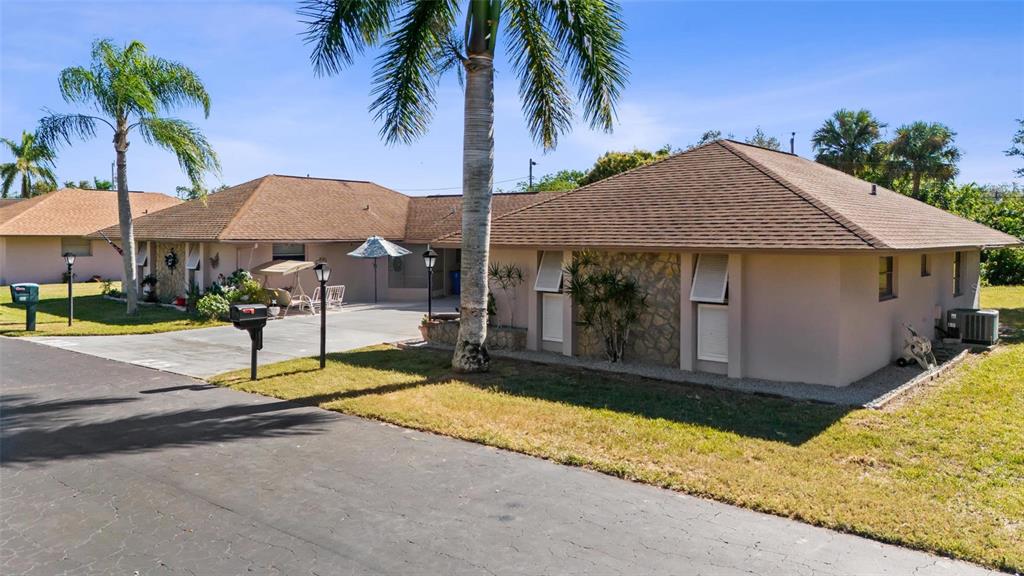 A low-slung, tan-colored house with a brown shingled roof and a palm tree out front — 235 THISTLE COURT, LEHIGH ACRES, FL