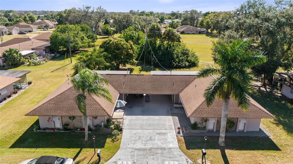 An aerial view shows a single-story duplex with a shared central carport and palm trees — 235 THISTLE COURT, LEHIGH ACRES, FL