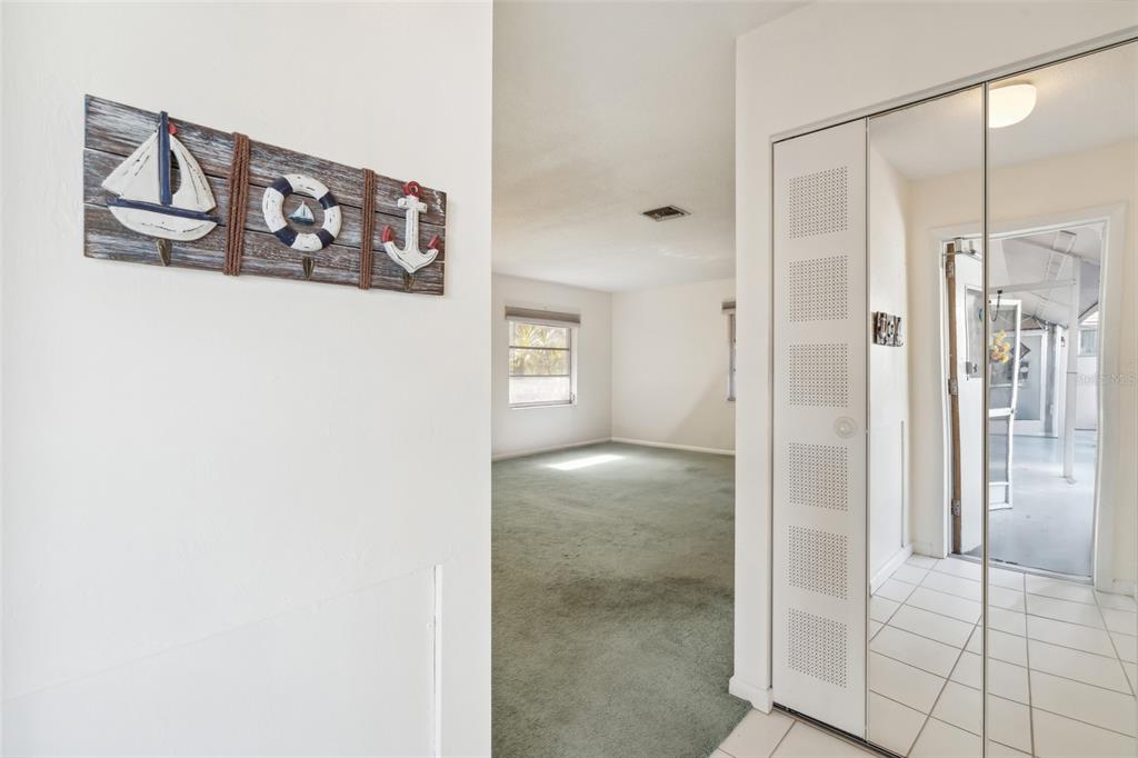 A view from a tiled entryway into a carpeted living room with nautical wall decor — 235 THISTLE COURT, LEHIGH ACRES, FL