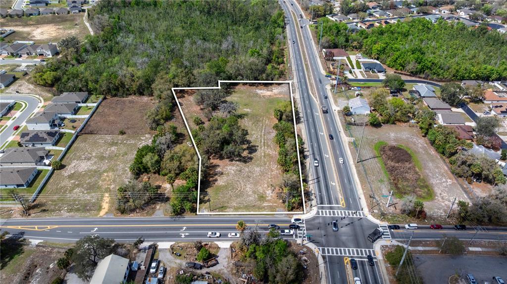 An aerial view shows a vacant, rectangular lot bordered by a road and residential homes — 711 RONALD REAGAN PARKWAY, DAVENPORT, FL