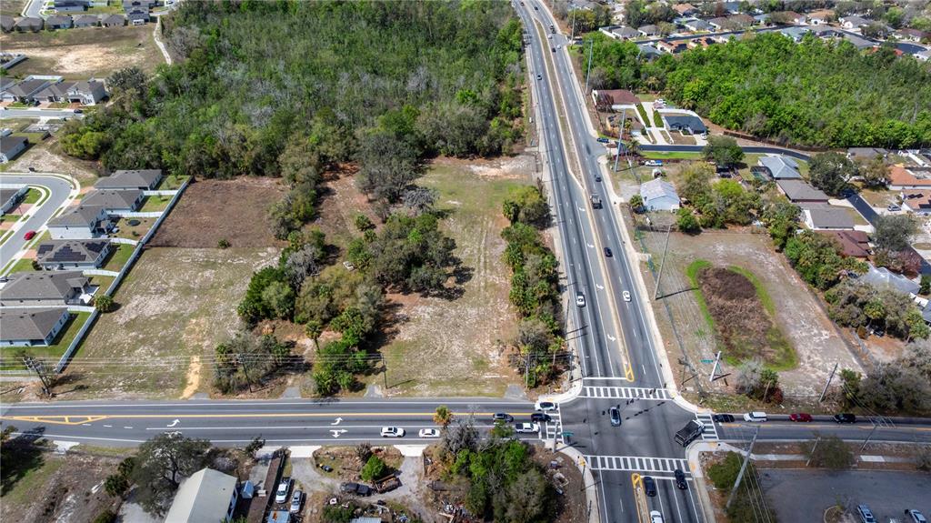 An aerial view shows a vacant, wooded lot situated next to a multi-lane road intersection — 711 RONALD REAGAN PARKWAY, DAVENPORT, FL