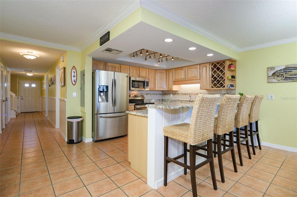 A kitchen with light wood cabinets, granite countertops, stainless steel appliances, and a breakfast bar — 4421 S ATLANTIC AVENUE UNIT A2, PONCE INLET, FL