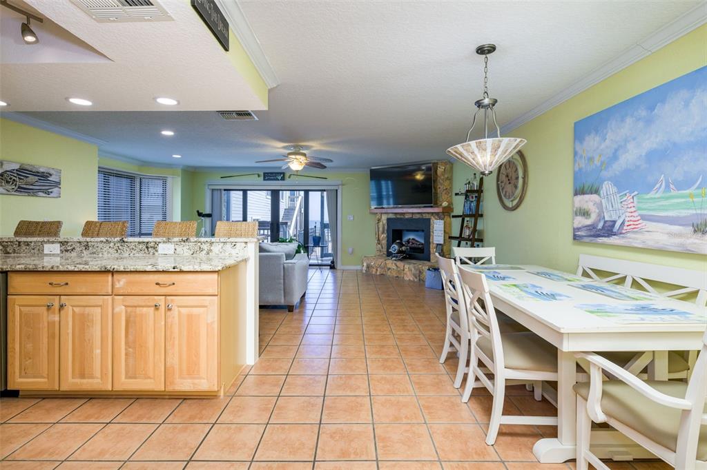 An open-concept living and dining area features tile flooring, a stone fireplace, and light cabinetry — 4421 S ATLANTIC AVENUE UNIT A2, PONCE INLET, FL