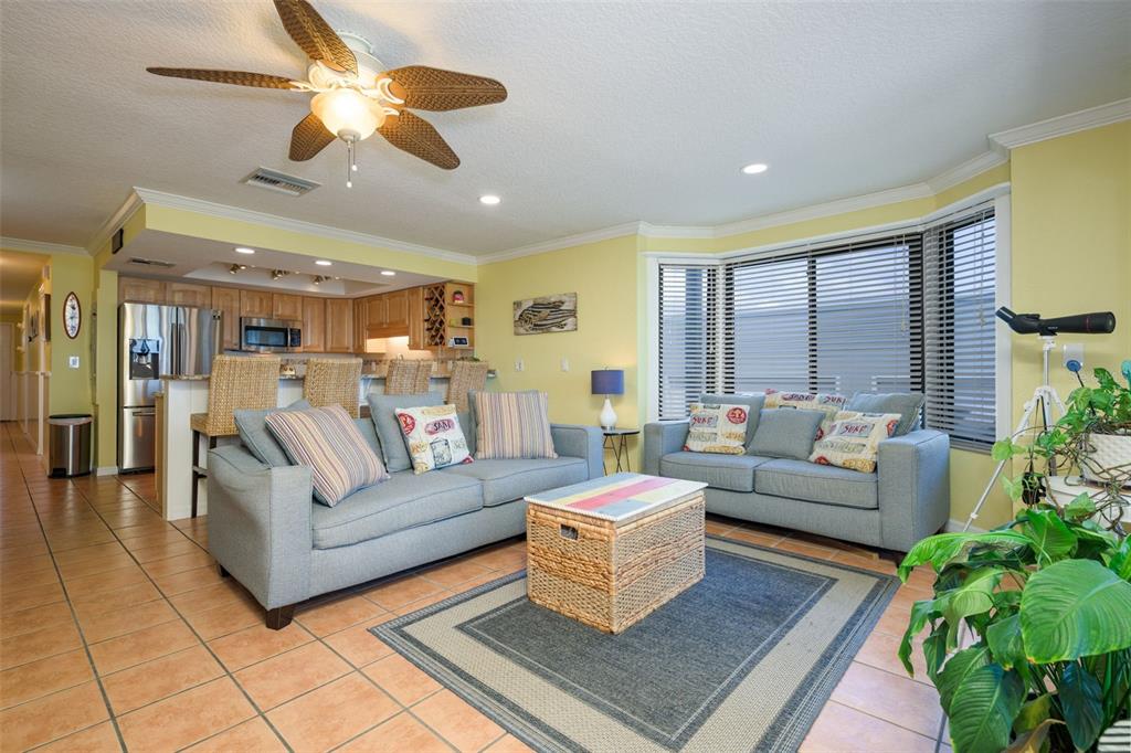 A living room with two blue sofas, a wicker coffee table, and an open kitchen — 4421 S ATLANTIC AVENUE UNIT A2, PONCE INLET, FL