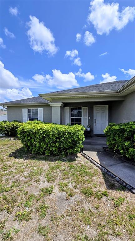The front exterior of a single-story house features a white door and green landscaping — 706 NW 1ST LANE, CAPE CORAL, FL