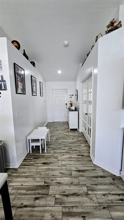 A bright hallway features wood-look tile flooring, white walls, and a small children's table set — 706 NW 1ST LANE, CAPE CORAL, FL