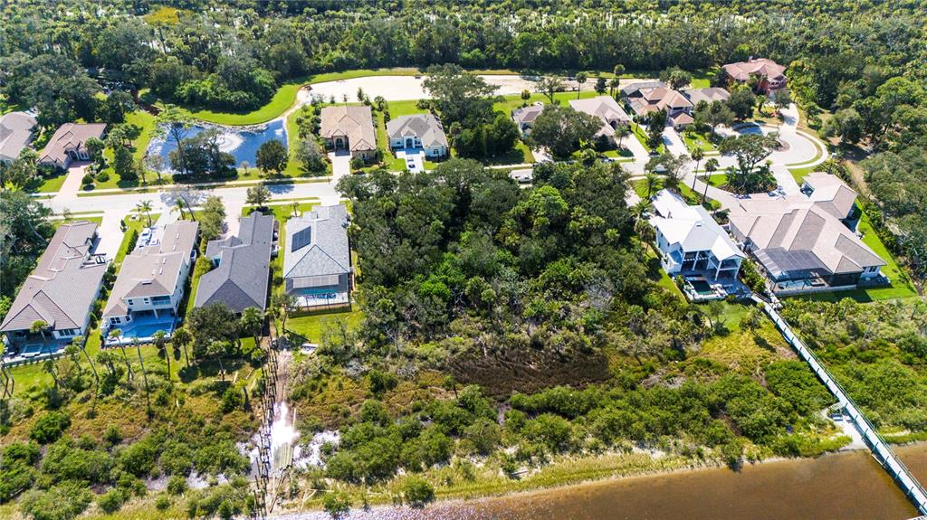 An aerial view shows several houses situated along a waterfront with a wooden pier — 62 N RIVERWALK DRIVE, PALM COAST, FL