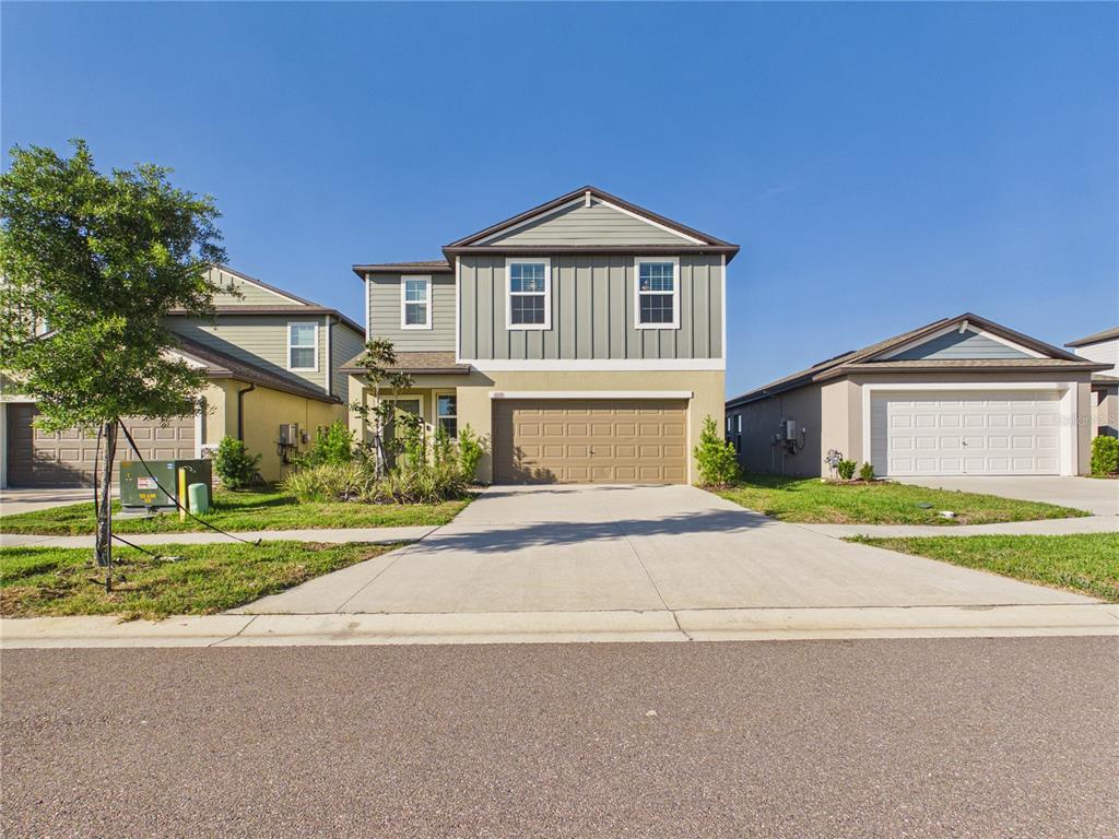 A two-story suburban house with a tan stucco base, gray vertical siding, and a garage — 1874 LANIER ROAD, ZEPHYRHILLS, FL