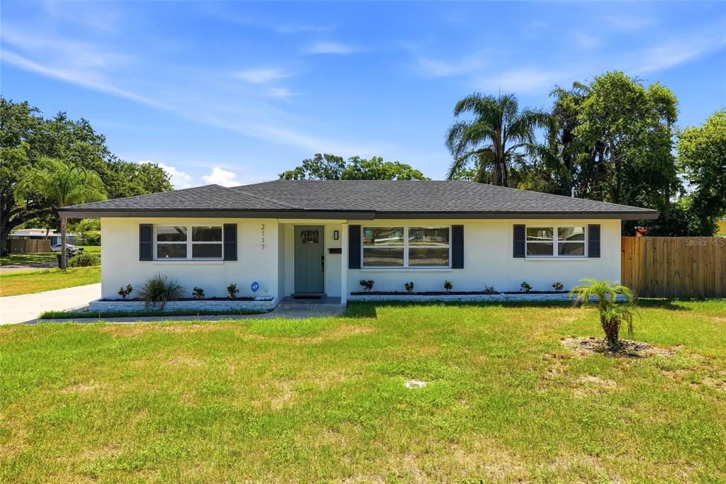 A single-story house with white stucco walls, a dark roof, and a green front door — 2117 N HERCULES AVENUE, CLEARWATER, FL