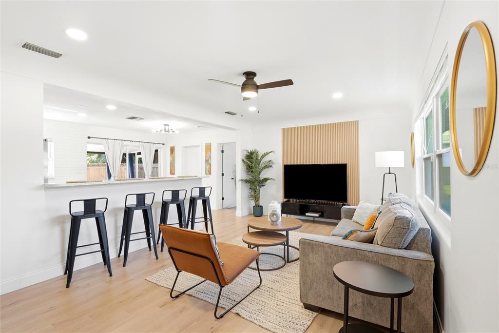A living room features a wood-slat accent wall, a gray sofa, and a breakfast bar — 2117 N HERCULES AVENUE, CLEARWATER, FL
