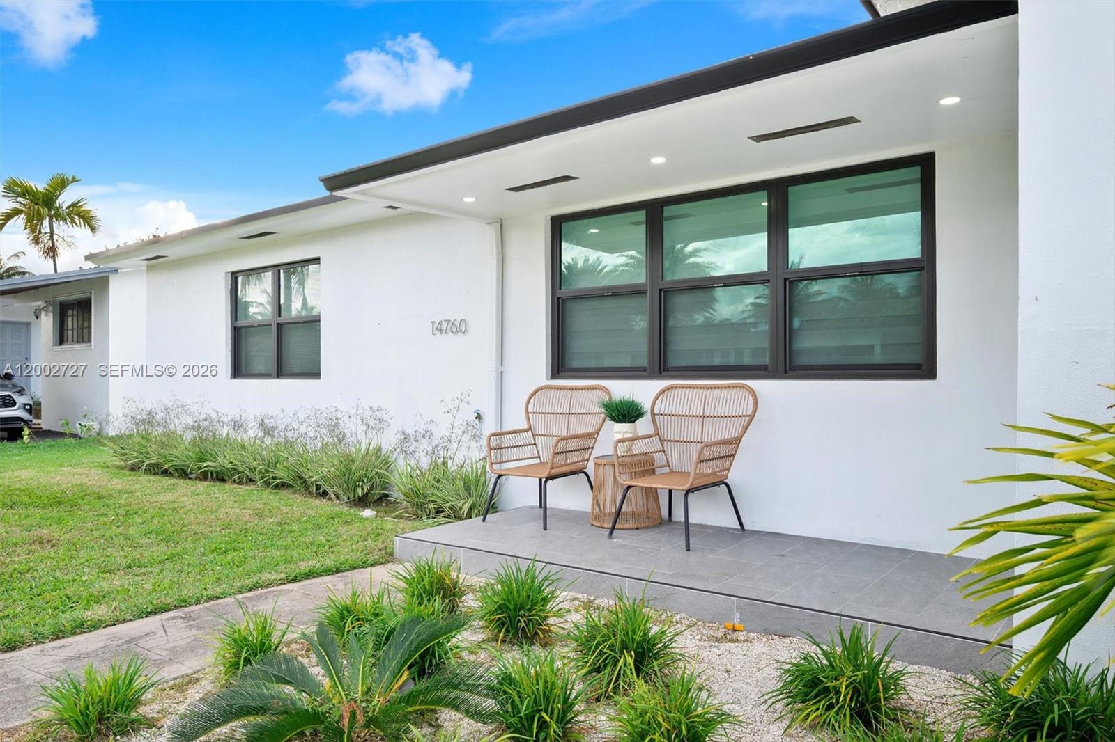 A white house exterior features a gray tiled porch with two wicker chairs — 14760 S Spur Dr, Miami FL 33161, MIAMI, FL