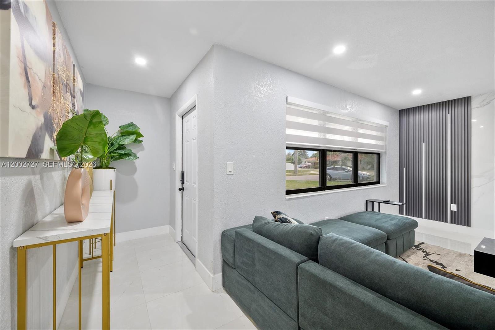A living room features a teal sectional sofa, a white console table, and a window — 14760 S Spur Dr, Miami FL 33161, MIAMI, FL