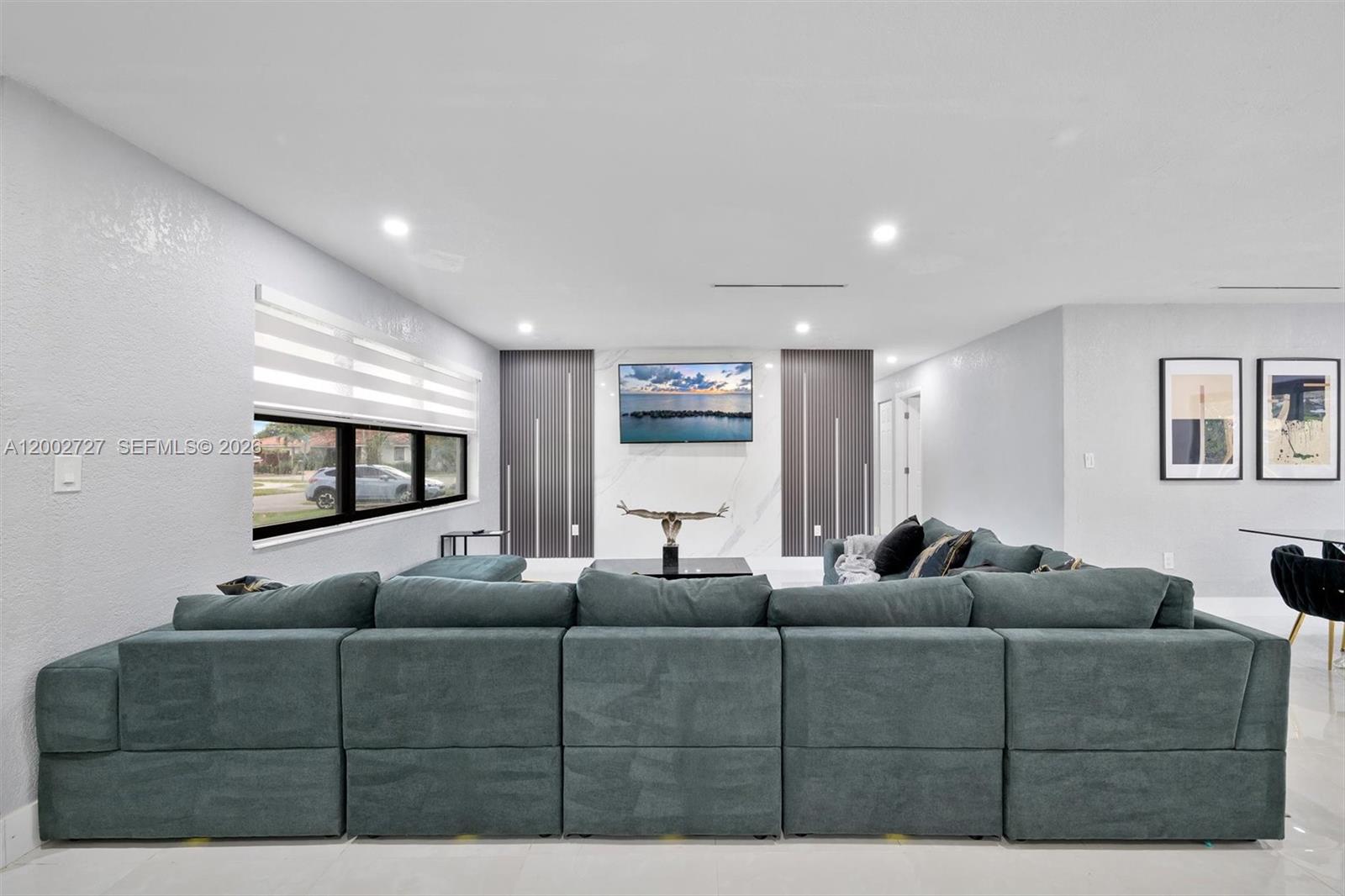 A modern living room features a large teal sectional sofa facing a wall-mounted television — 14760 S Spur Dr, Miami FL 33161, MIAMI, FL