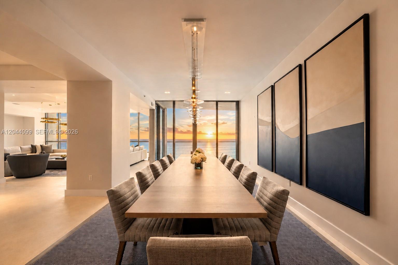 A dining room features a long wooden table, upholstered chairs, and large ocean-view windows — 5959 Collins Ave, Miami Beach FL 33140, MIAMI BEACH, FL