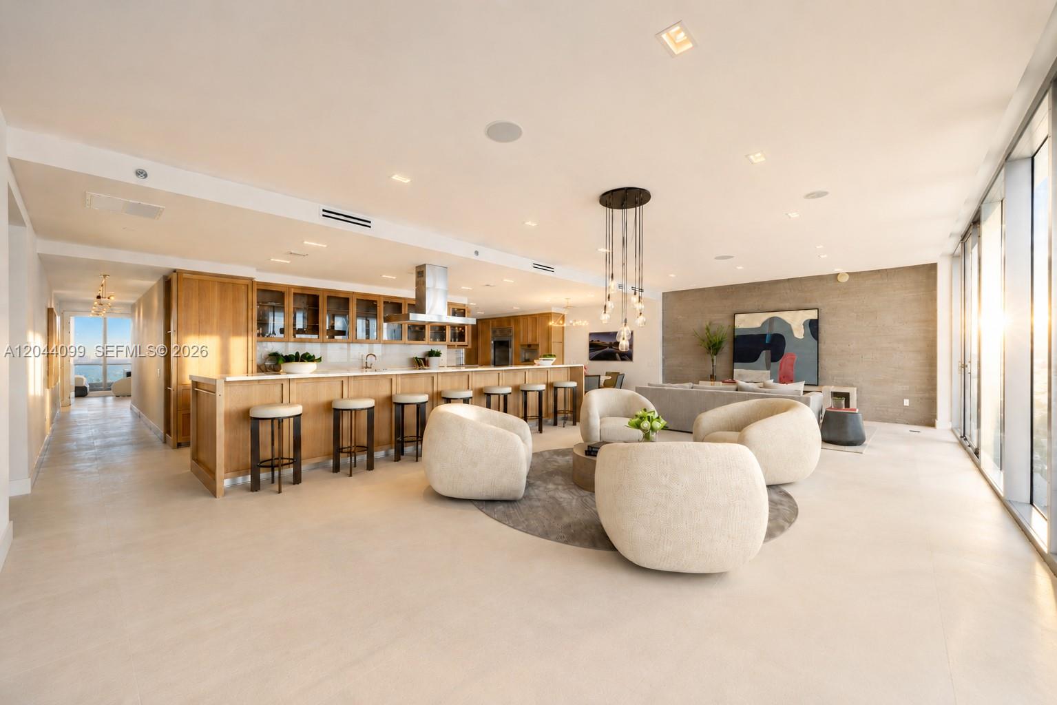 A modern open-concept living area features a kitchen with wood cabinetry and a seating lounge — 5959 Collins Ave, Miami Beach FL 33140, MIAMI BEACH, FL