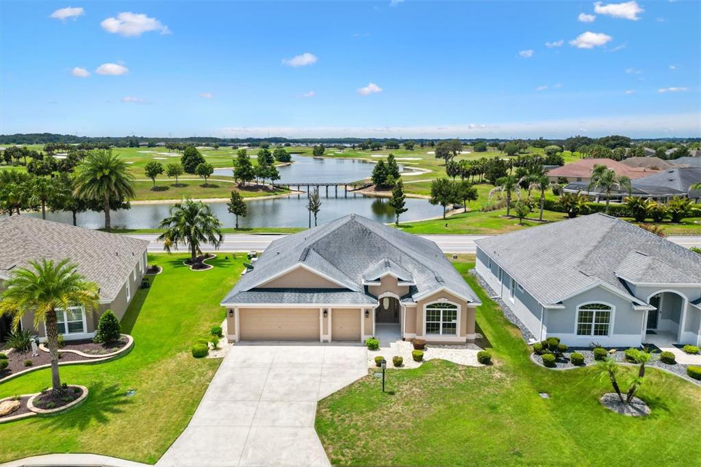 An aerial view shows a suburban house with a driveway facing a lake and golf course — 486 INDEPENDENCE PATH, THE VILLAGES, FL
