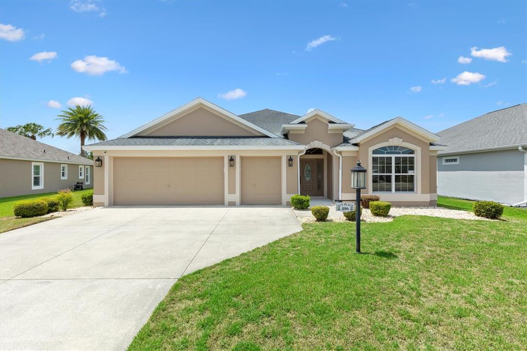 A single-story suburban house with a three-car garage and a landscaped front yard — 486 INDEPENDENCE PATH, THE VILLAGES, FL