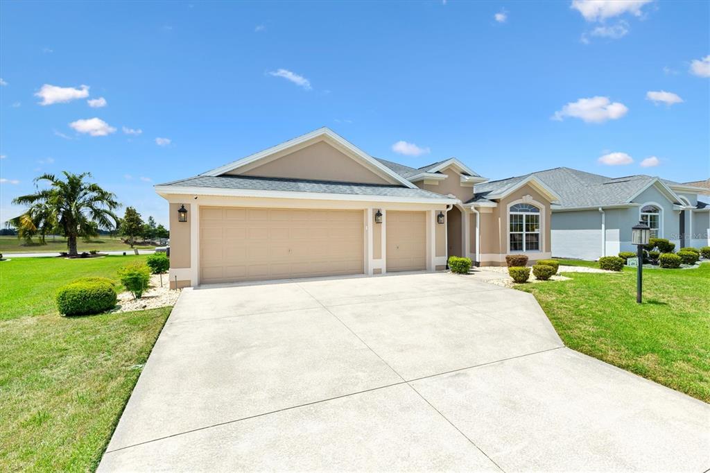 A beige single-story house with a three-car garage and a concrete driveway — 486 INDEPENDENCE PATH, THE VILLAGES, FL