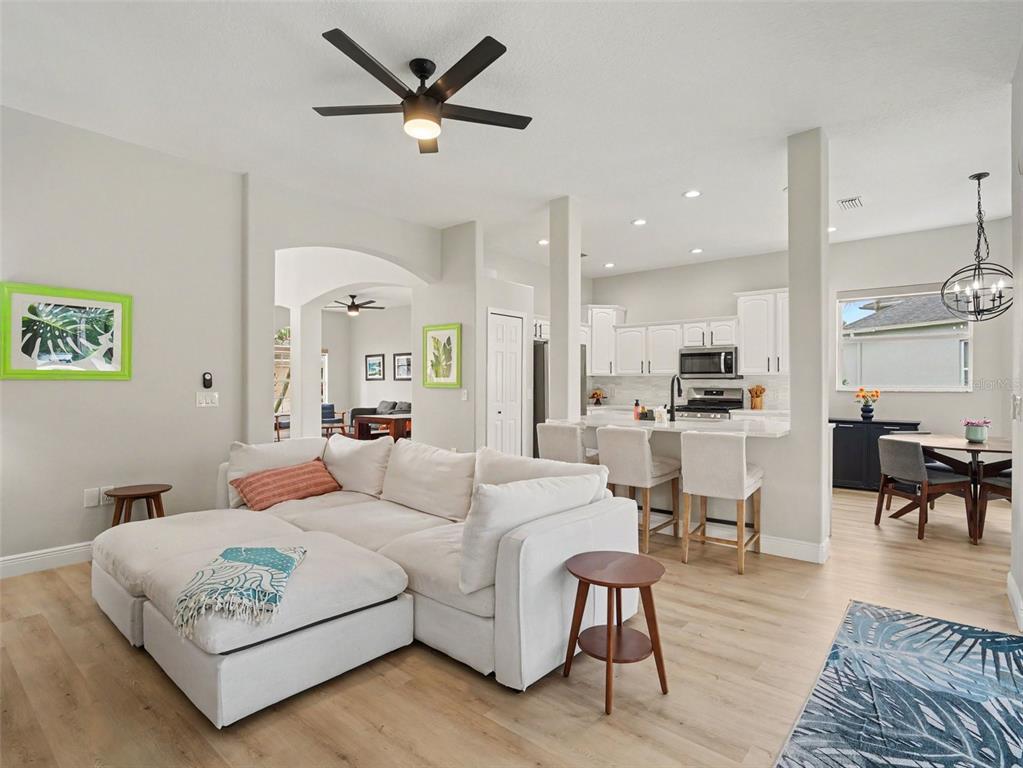 A living room with a white sectional sofa opens to a kitchen with bar seating — 14146 CATTLE EGRET PL, LAKEWOOD RANCH, FL