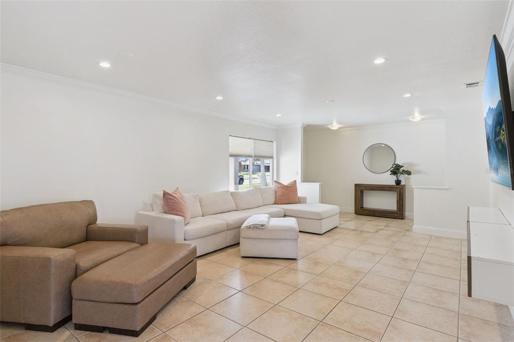 A living room features a white sectional sofa, a brown armchair, and light tile flooring — 3205 CAULFIELD STREET, APOPKA, FL
