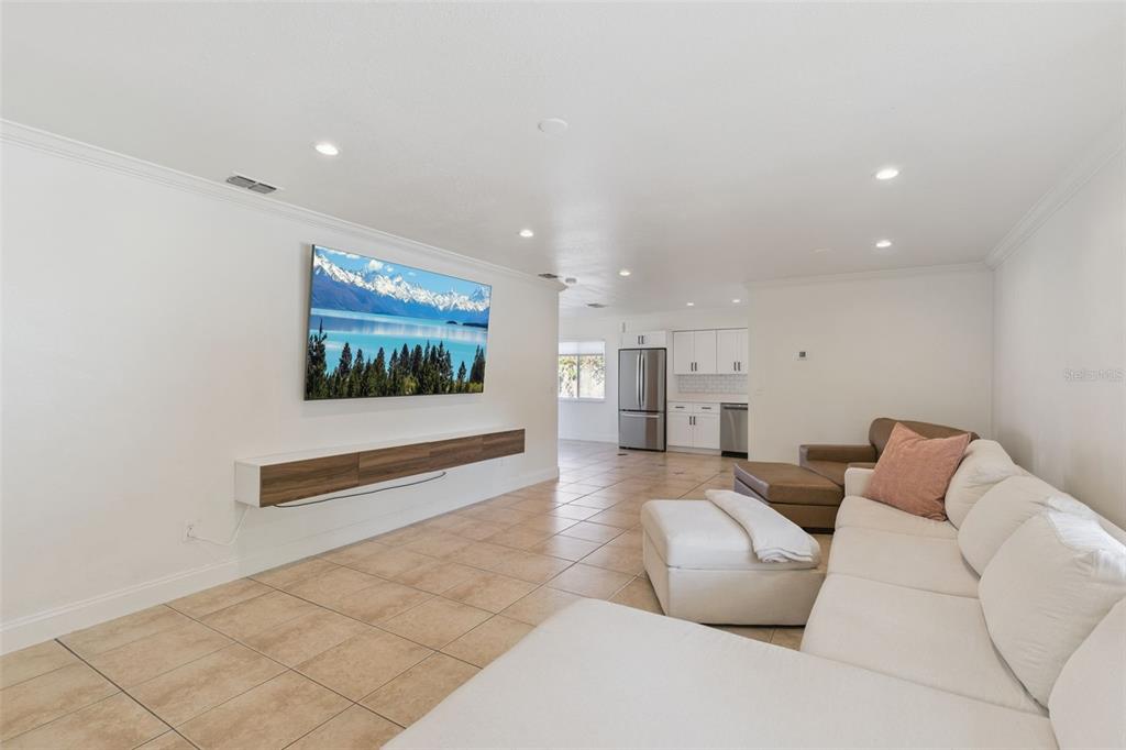 A living room features a wall-mounted television, floating console, tile flooring, and white sofa — 3205 CAULFIELD STREET, APOPKA, FL