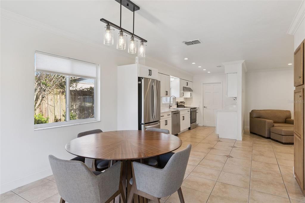 A kitchen and dining area with a round wooden table, gray chairs, and tile flooring — 3205 CAULFIELD STREET, APOPKA, FL