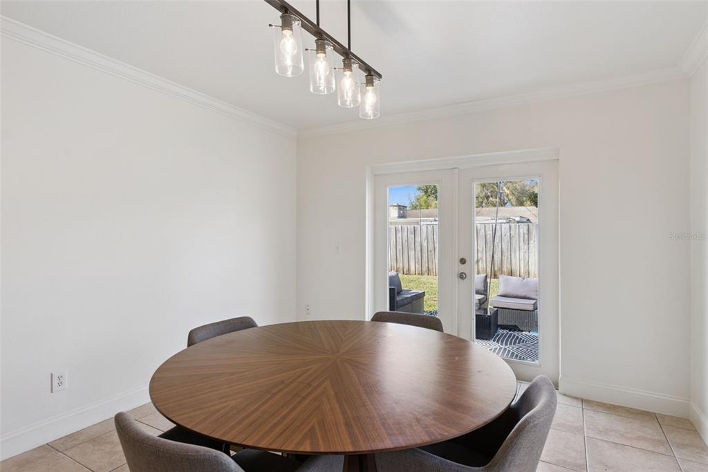 A dining room features a round wooden table, four gray chairs, and glass-paned patio doors — 3205 CAULFIELD STREET, APOPKA, FL