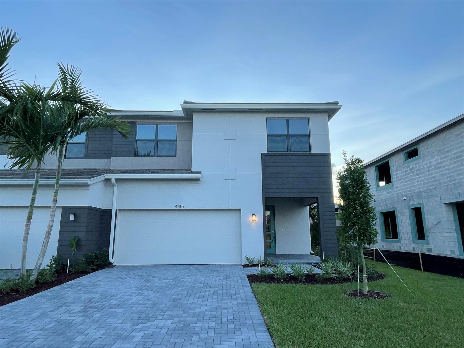 A modern two-story townhouse features a white facade, dark gray accents, and a paved driveway — 4415 Arcturus Lane, Lake Worth FL 33467, LAKE WORTH, FL